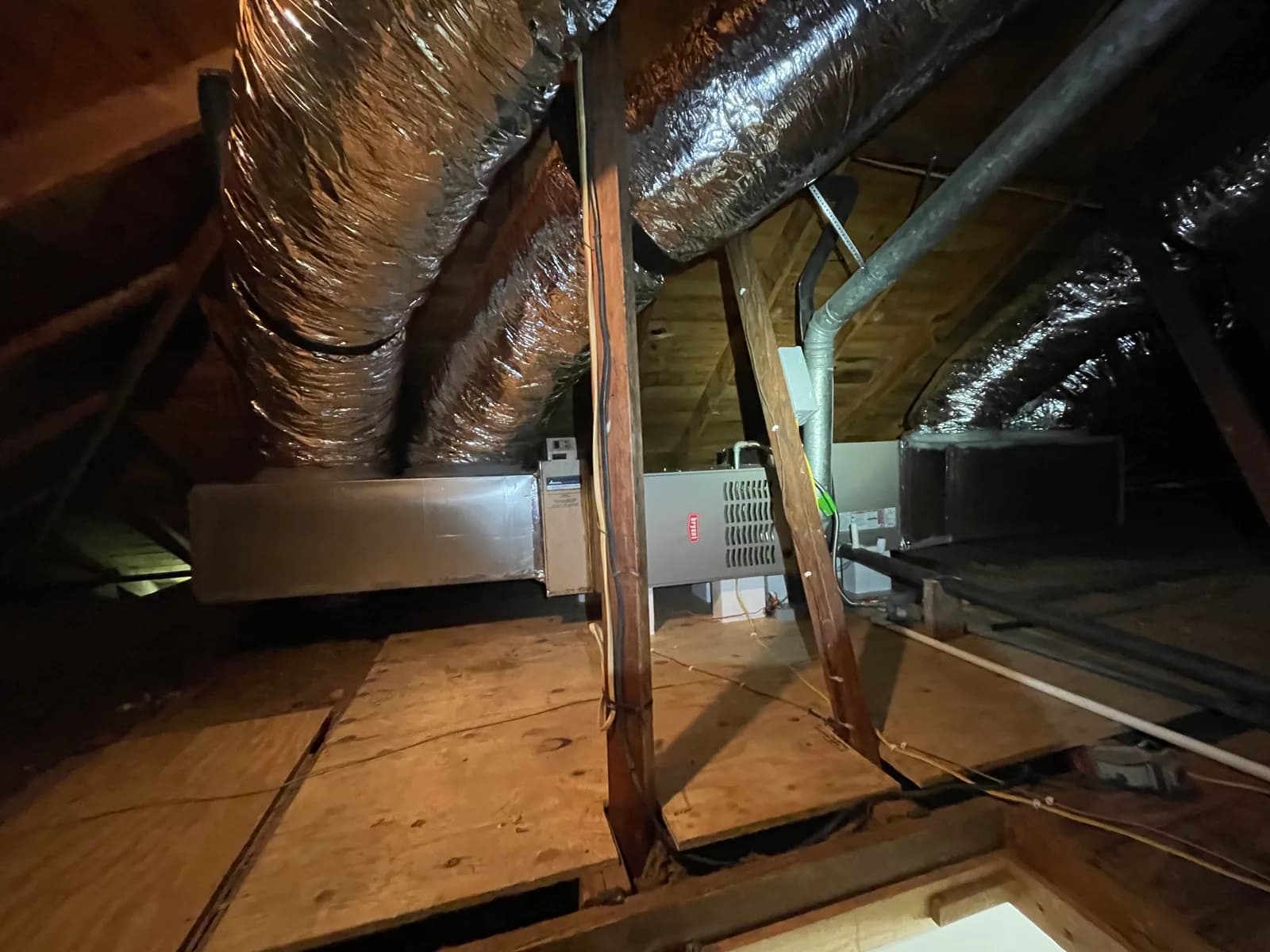 Horizontal Bryant heating equipment with metal vent piping and surrounding attic ductwork.